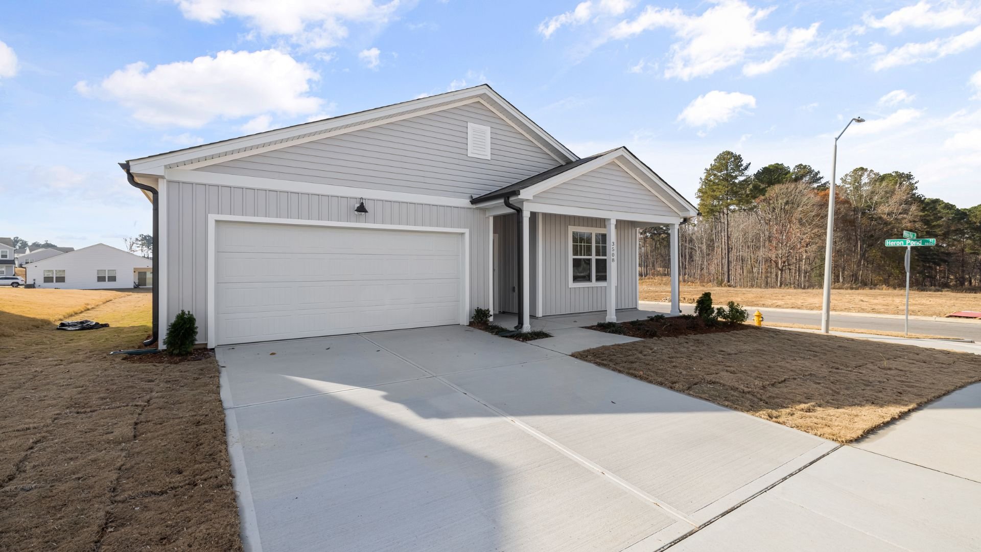 New gray single-story house with white garage and concrete driveway